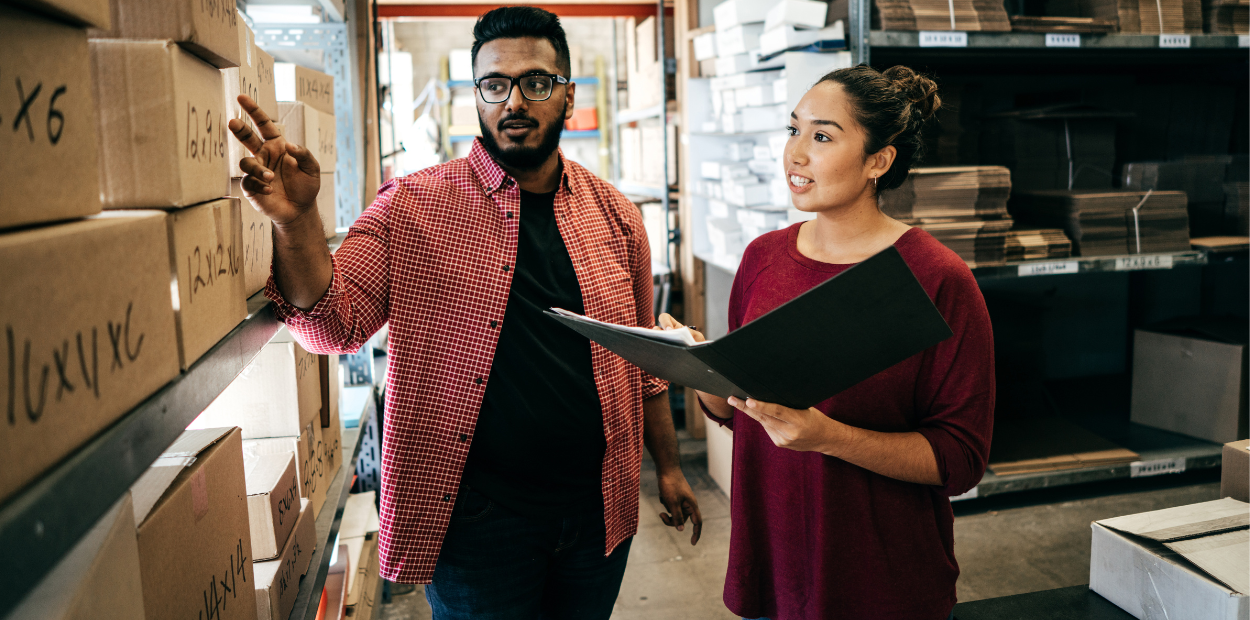 A man and a women in a store room reviewing stock levels. 